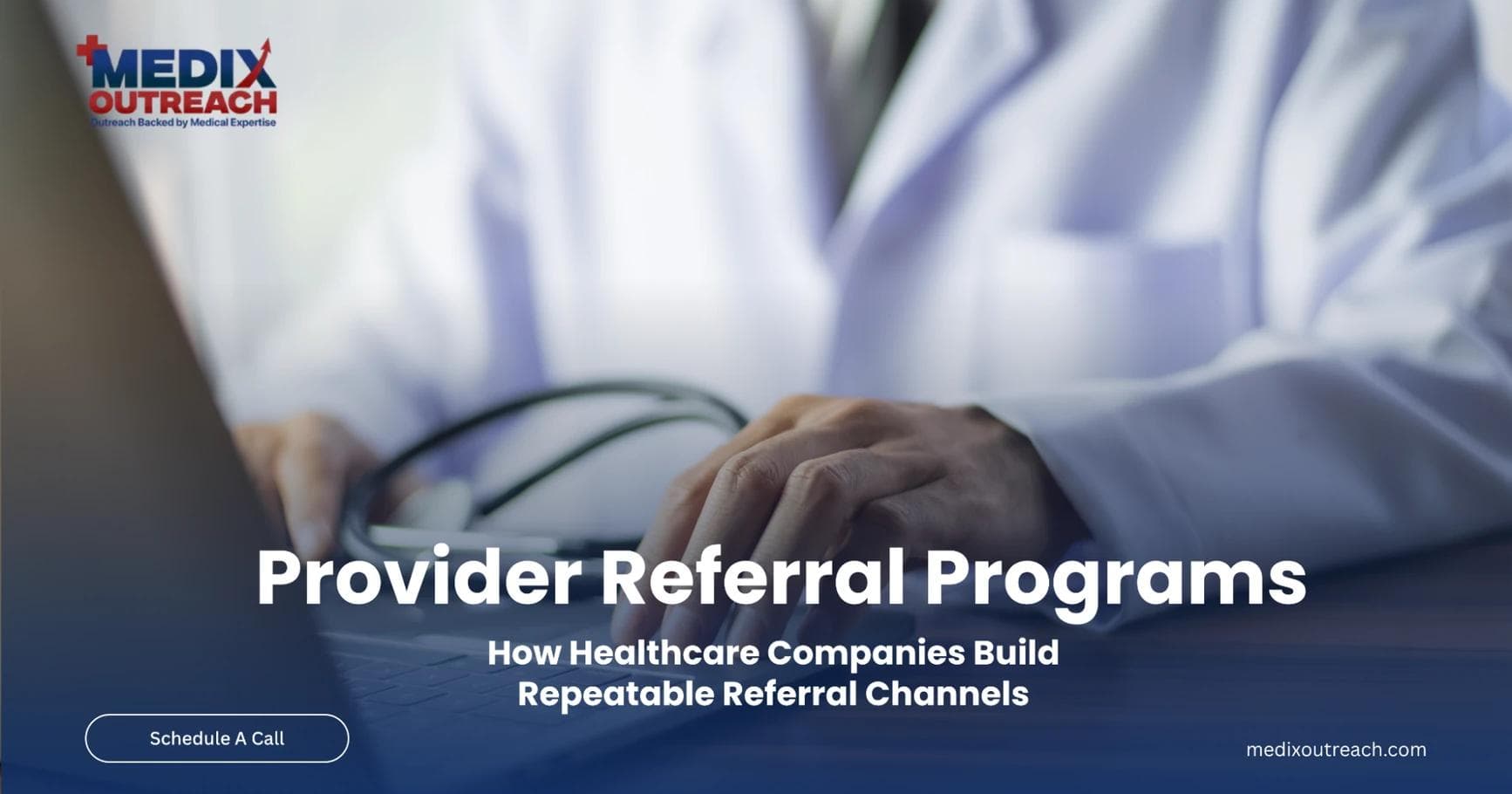 A clinician working at a laptop while reviewing provider referral information.
