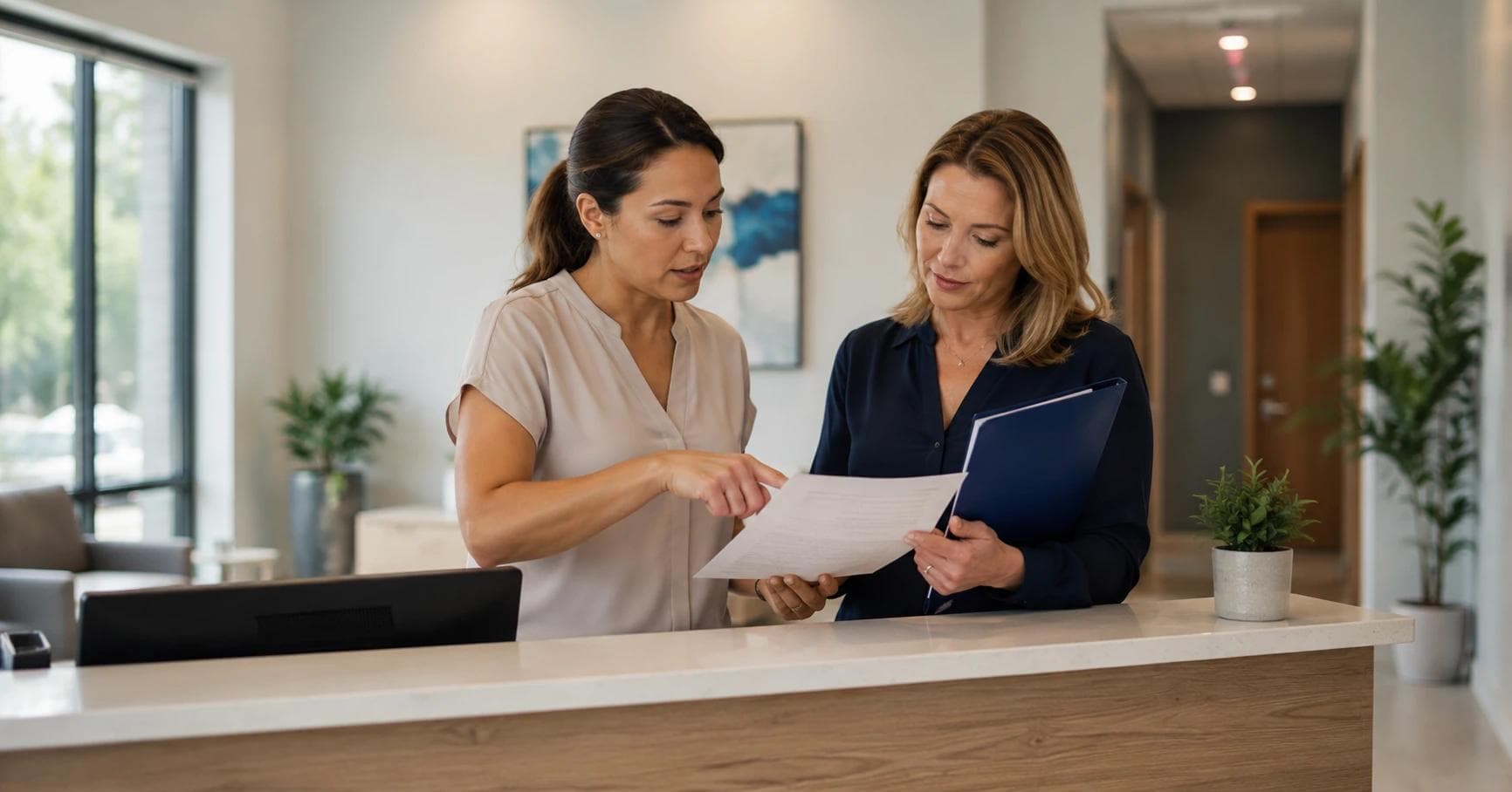 Practice manager and clinic owner reviewing paperwork at a front office desk